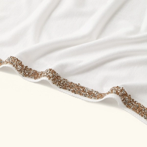 Macro view of white soft fabric headscarf with glittering gold and silver rhinestone trim
