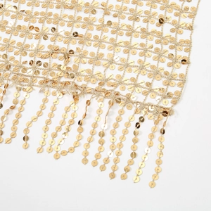 Detail shot of golden sequin mesh fabric with metallic luster and long tassel fringe