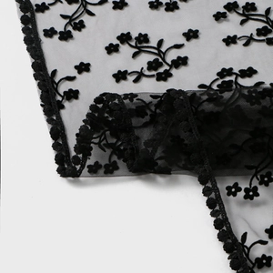 Détail de dentelle florale noire avec broderie de fleurs et bordures ondulées délicates