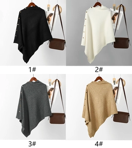 Detail view of four-color knit ponchos with high neck, asymmetric hem, and gold buttons