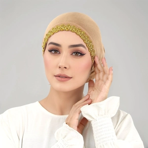 Dettaglio ravvicinato del turbante beige con ricamo in pizzo floreale dorato