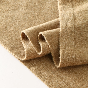 Macro detail of camel knit shawl with thick boucle texture and wide edge stitching