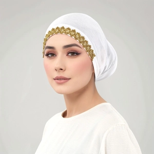 Dettaglio di turbante bianco con pizzo floreale dorato e tessuto a maglia morbida plissettata