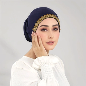 Dettaglio del turbante blu scuro con ricamo floreale in pizzo dorato sul bordo frontale