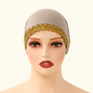 Dettaglio del turbante color kaki con bordo in pizzo dorato su un modello a manichino