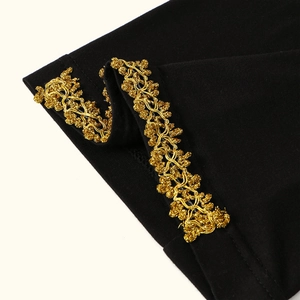 Dettaglio del bordo in maglia nera con raffinato ricamo in pizzo floreale dorato