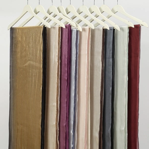 Elegantes bufandas largas degradadas en varios colores metálicos en perchas de madera