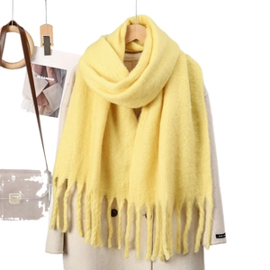 Écharpe jaune vif effet cachemire avec longues franges portée sur un manteau blanc