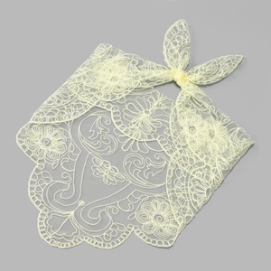 Macro detail of intricate floral lace embroidery on a light cream triangle headscarf