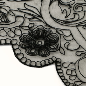 Detailed macro view of black embroidered lace featuring sunflower patterns and floral texture