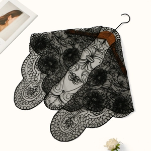 Detailed close-up of intricate black floral embroidery on a vintage lace shawl