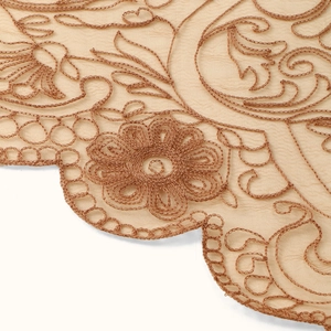 Detailed macro shot of elegant floral lace embroidery with scalloped edges and beige patterns