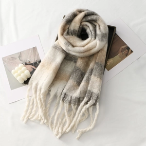 Close-up of thick winter scarf with beige plaid pattern and handmade knotted fringe tassels