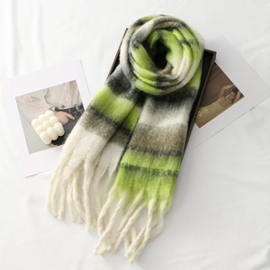 Close-up of green and grey thick plaid scarf with soft fringe details in a cozy setting