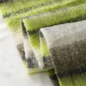 Detail of thick plush color-block scarf with green and grey stripes and soft texture