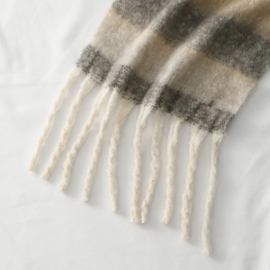 Macro detail of thick plaid scarf featuring long tassels and soft plush wool texture