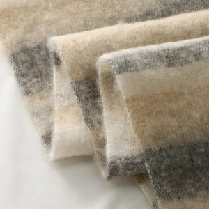 Close-up of thick plaid scarf fabric showing soft brushed texture and beige grey check