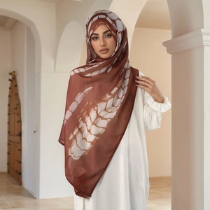 Detail of elegant dark brown Muslim hijab with white tie-dye feather patterns for women