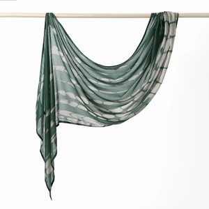 Detail of dark green printed headscarf draped on a wooden pole with abstract wavy patterns