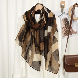 Détail d'une écharpe en georgette fine à motifs géométriques marron sur un cintre en bois