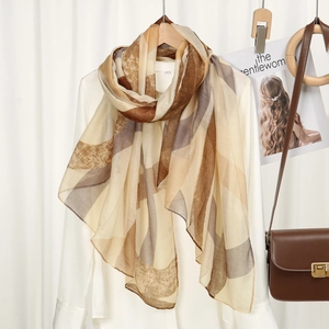 Écharpe en soie georgette à motif géométrique sur un cintre avec sac en cuir marron