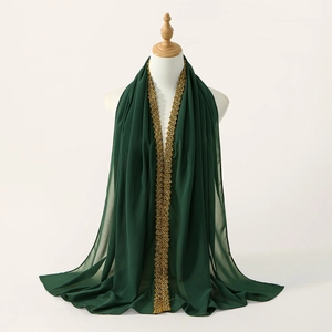 Detailed close-up of dark green chiffon scarf with golden floral embroidery