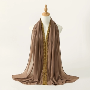 Close-up of brown chiffon scarf with elegant gold floral embroidery on scalloped edges