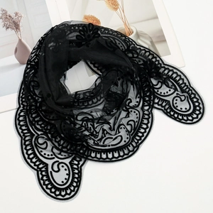 Detailed view of black lace shawl with intricate embroidery on minimalist background