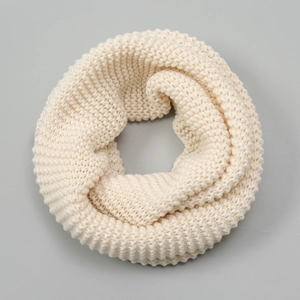 Close-up detail of cream white thick cable knit infinity scarf with cozy ribbed texture