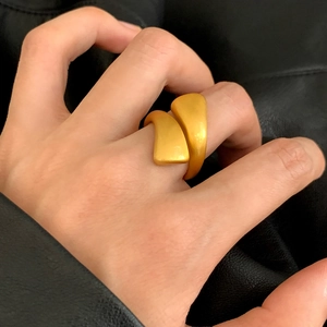 Modern brushed gold bypass ring with abstract geometric design worn on a finger
