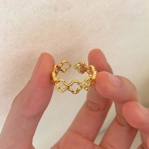 Detailed view of a gold open ring featuring hollow quatrefoil patterns and embossed textures