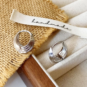 Detailed close-up of silver multi-layered hoop earrings with a polished metallic finish