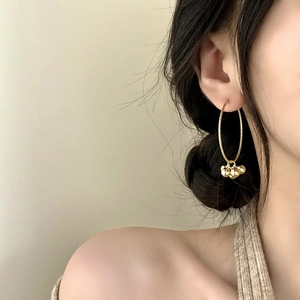 Élégantes créoles dorées avec pendentifs en sphère métallique portées par un mannequin