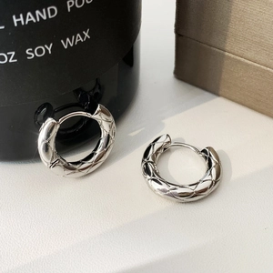 Detailed view of silver quilted pattern hoop earrings on a luxury jewelry box
