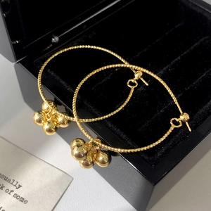 Détail de créoles dorées avec cinq pendentifs boules métalliques polies dans un écrin noir
