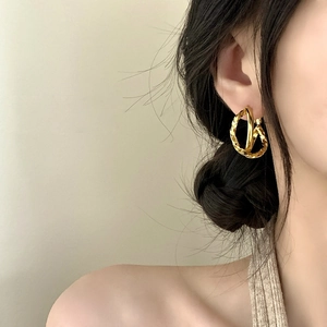 Elegant gold twisted hoop earrings with a braided texture shown on a female model
