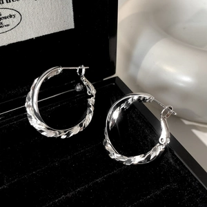 Macro detail of S925 sterling silver hoop earrings with triple twisted texture on black velvet