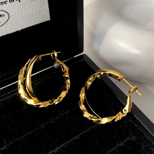 Detailed view of intertwined gold hoop earrings with smooth and twisted texture detail