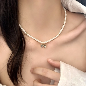 Élégant collier de perles avec pendentif nœud doré porté par un mannequin