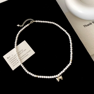 Détail du collier de perles avec pendentif nœud doré sur fond de velours noir
