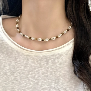 Collier élégant en perles et œil de faucon avec motif floral porté par un mannequin
