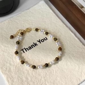 Détail d'un bracelet de perles avec œil de tigre et perles blanches sur une carte