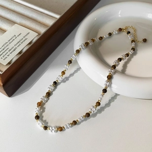 Détail d'un collier élégant en perles et œil de tigre avec fermoir doré sur céramique