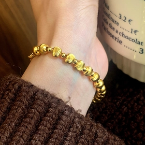 Luxurious gold beaded bracelet with matte textured and polished spheres on a female wrist