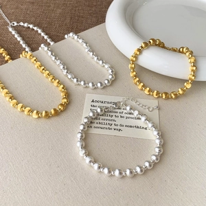 Detail of brushed gold and silver bead chain jewelry with adjustable lobster clasp closure