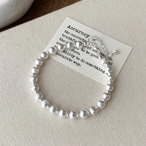Close-up of adjustable silver beaded bracelet with alternating smooth and textured metal spheres