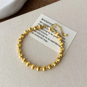 Detail of matte and polished gold beaded bracelet with lobster clasp and extender