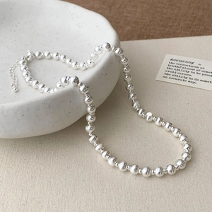 Detail of silver beaded necklace with brushed metal texture and adjustable extender chain