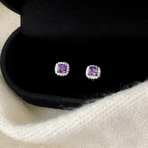 Gros plan sur les boucles d'oreilles en argent avec pierre violette et bordure zircon
