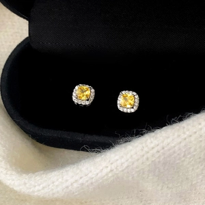 Gros plan de boucles d'oreilles halo en zircone jaune de coupe carrée dans un coffret